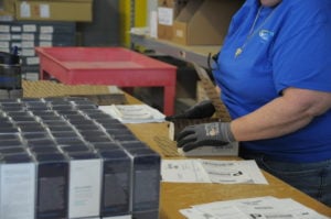 An lite prepcenter employee is shown putting packages together. Only her hands are visible, woorking on the task.