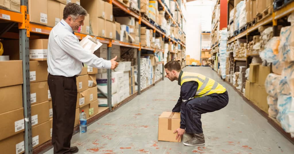 Warehouse worker being shown how to do a lifting technique